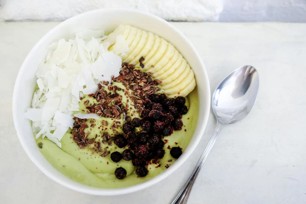 An avocado smoothie bowl is artfully sprinkled with coconut, cacao nibs, and other toppings