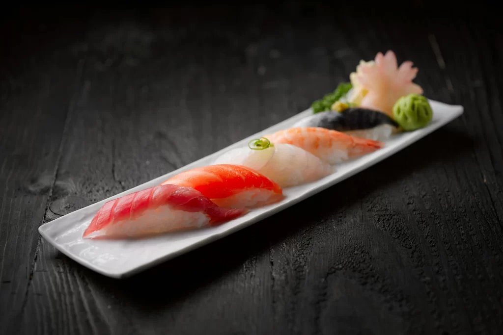 A sleek plate of sushi sits on a dark wood table.