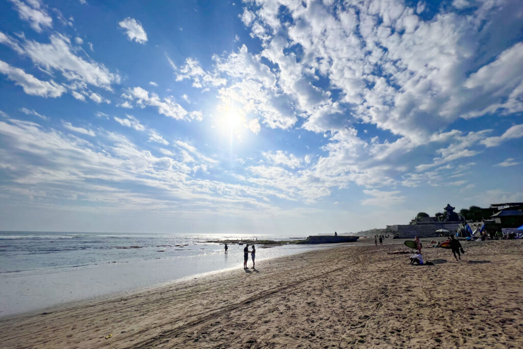 Tourists and surfers walk along Canggu Beach in Bali, Indonesia.