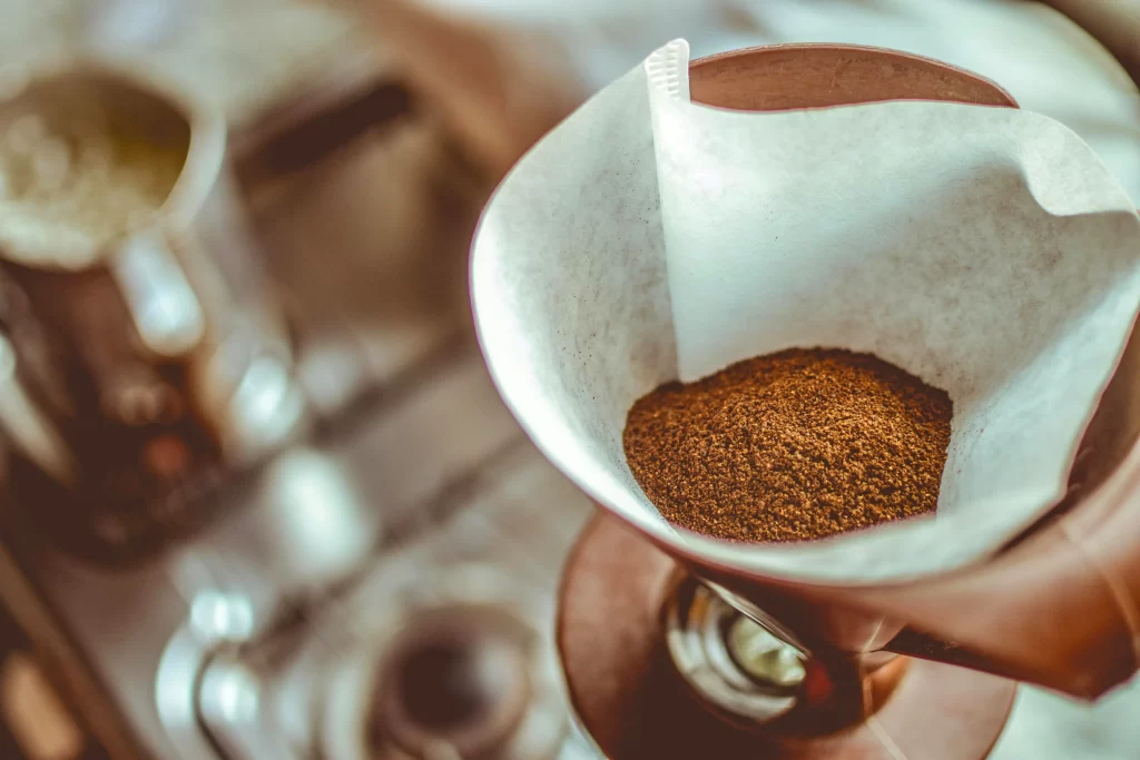Coffee grounds fill a paper coffee filter.