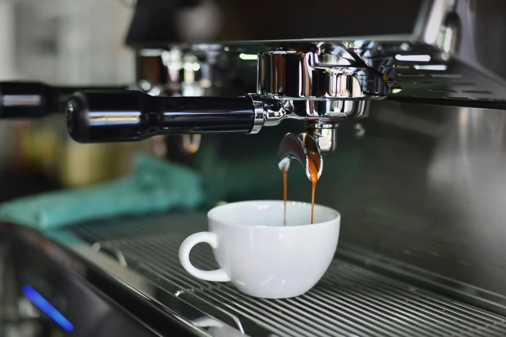 A commercial-grade espresso machine pours coffee into a white mug.