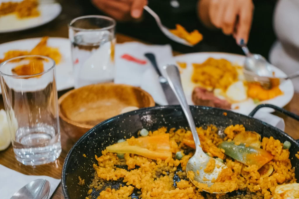A spoon rests in a half-eaten pan of paella.