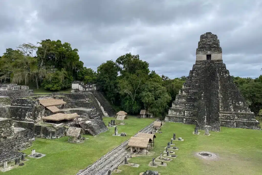 Recreated thatched huts and ruins of the ancient Mayan city of Tikal rise above the jungle.