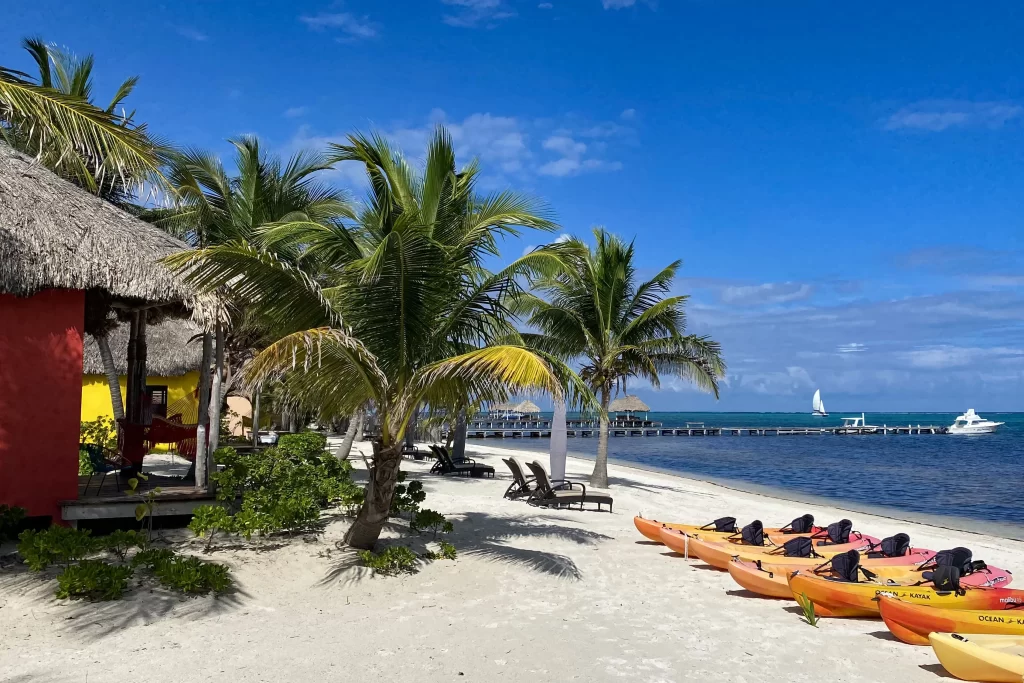 Kayaks line a tropical beach in Ambergris Caye, Belize. Ambergris Caye is the one of the top destinations on a Belize itinerary.
