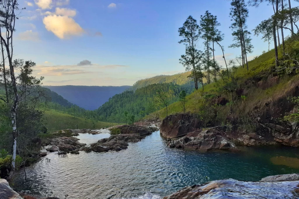 A natural swimming pool looks out over the green hills of Mountain Pine Ridge Forest Reserve in Belize's Cayo District.