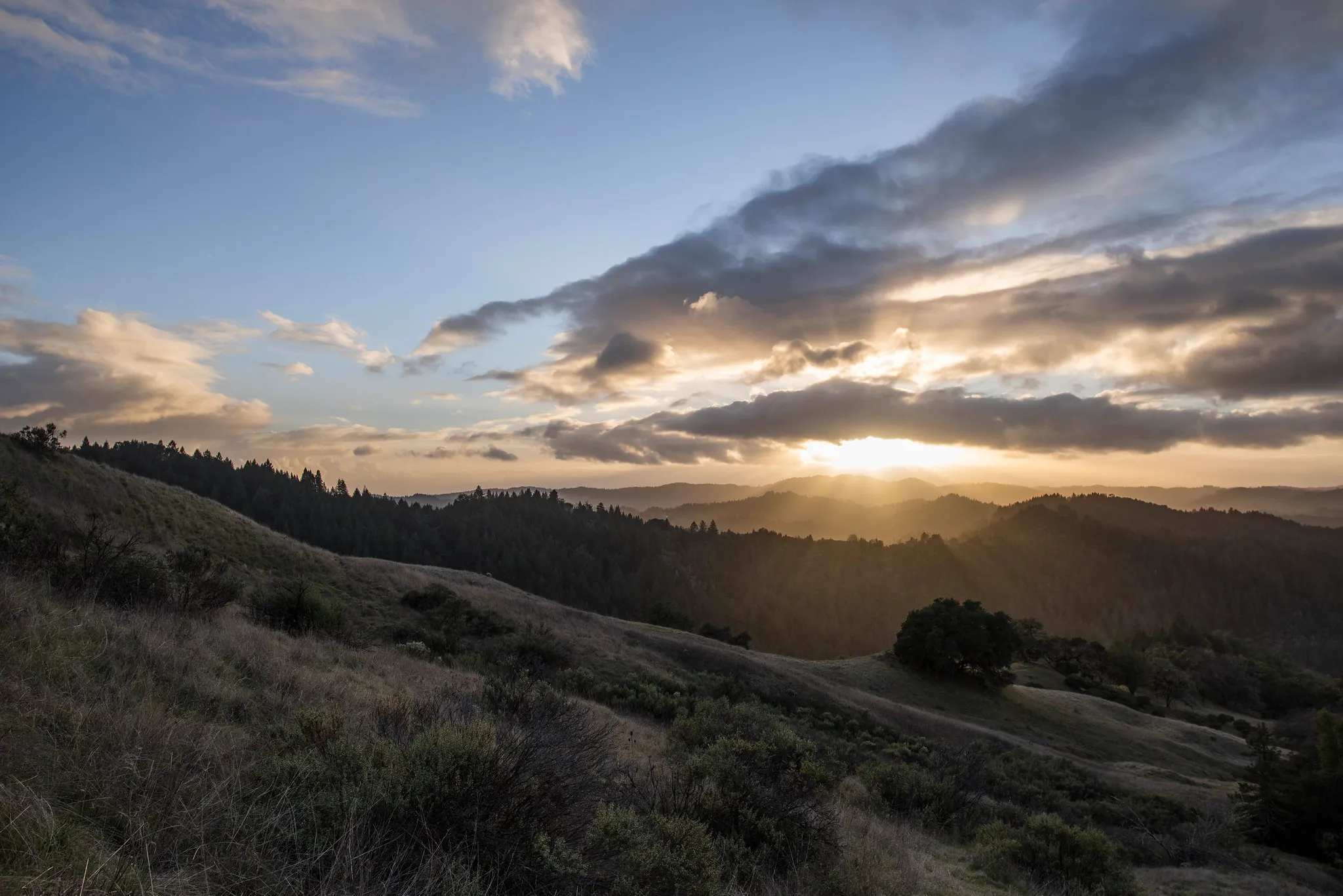 The sun sets behind clouds over the hills of Austin Creek State Recreation Area.