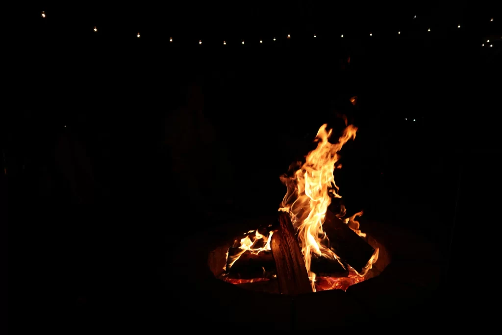 A wood-burning bonfire pit lights up a night sky.