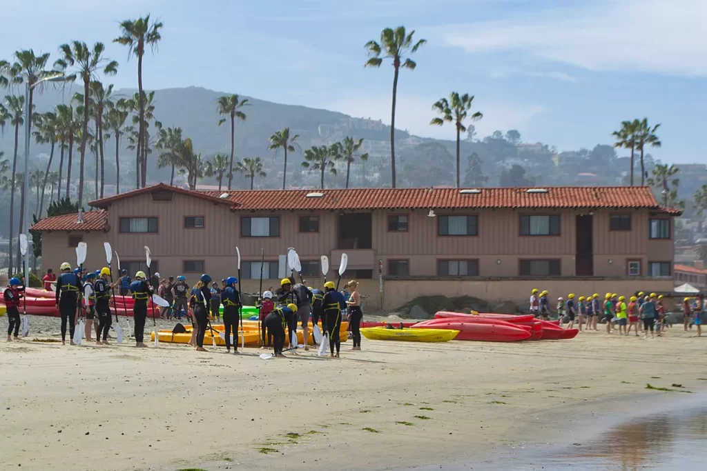 A kayaking tour reviews safety on the beach in La Jolla, California.