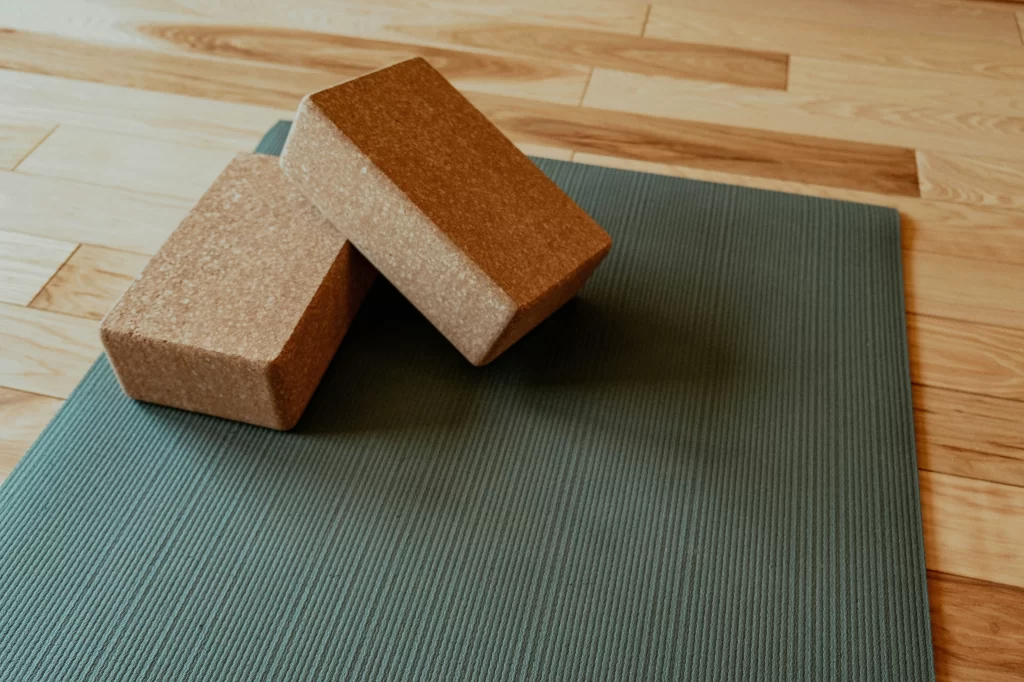 Two yoga blocks rest on a green yoga mat.