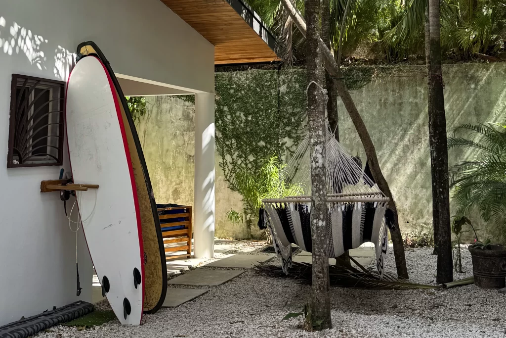 Two surfboards lean against a wall next to a striped hammock in Guiones, Costa Rica. The Guiones surfing break is one of the best in the region.