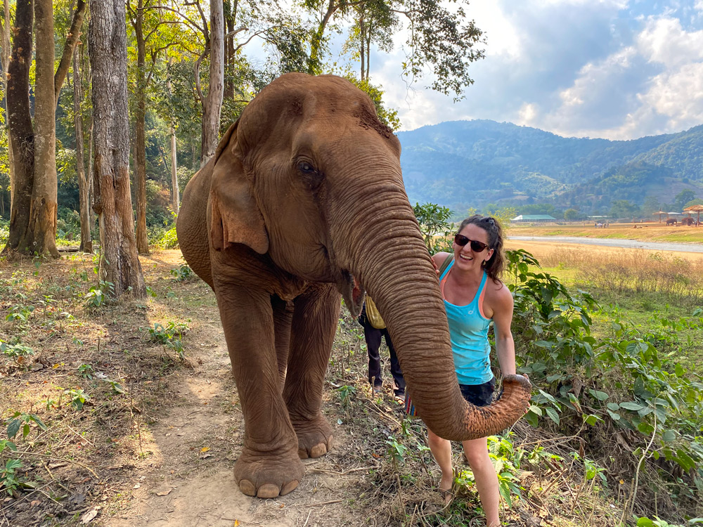 Girl walking with an elephant at Elephant Nature Park in Chiang Mai, Thailand