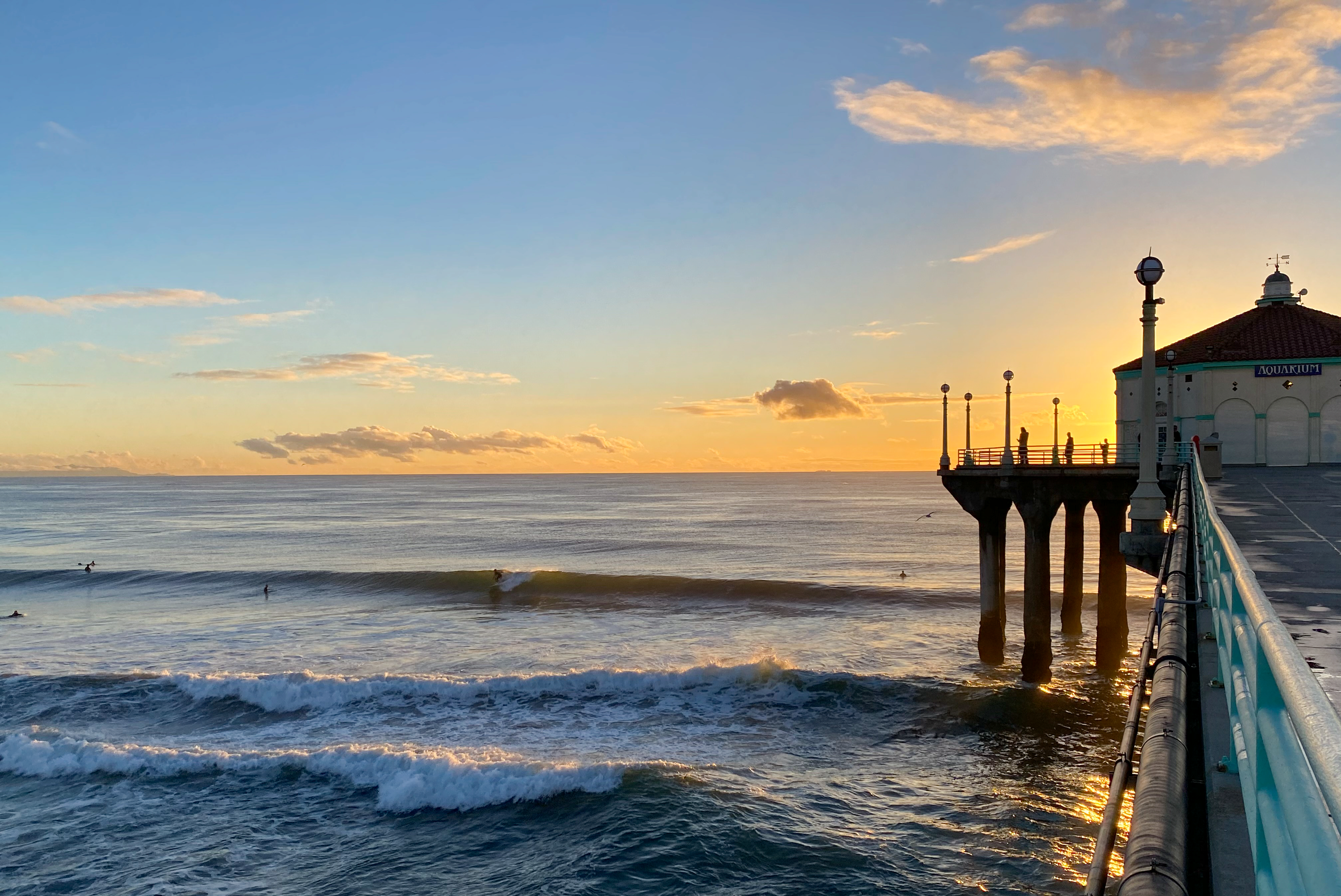 Surfers ride the waves off the Manhattan Beach Pier at sunset, in Los Angeles.