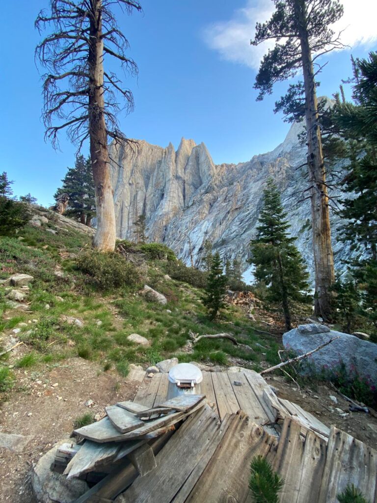 A rural pit toilet looks out to jagged mountain peaks along the High Sierra Trail.