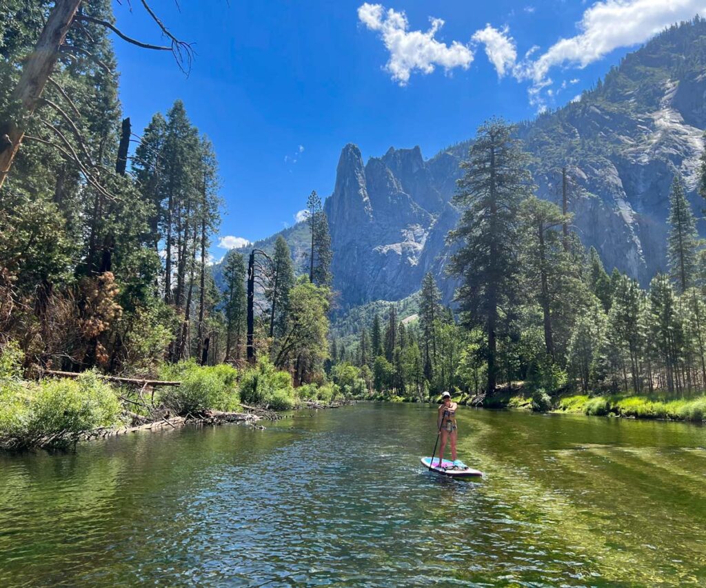 A paddle boarder paddles a stretch of the Merced River between Stoneman Bridge and Sentinel Beach in Yosemite Valley.