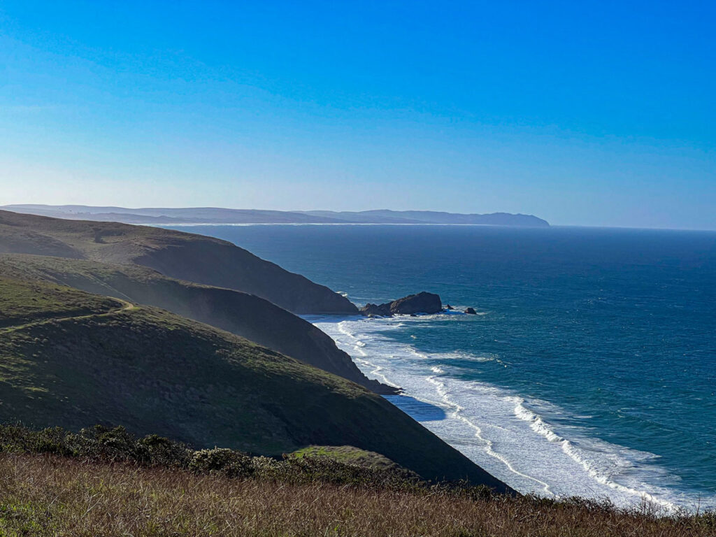 The Point Reyes headlands, appearing somewhat hazy as the morning fog burns off, with steep cliffs dropping down to the Pacific Ocean. 