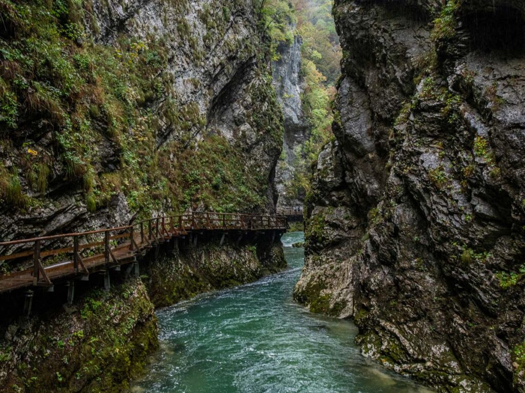 A raised wooden boardwalk above the Radovica River lines the narrow walls of Vintgar Gorge near Podham, Slovenia.