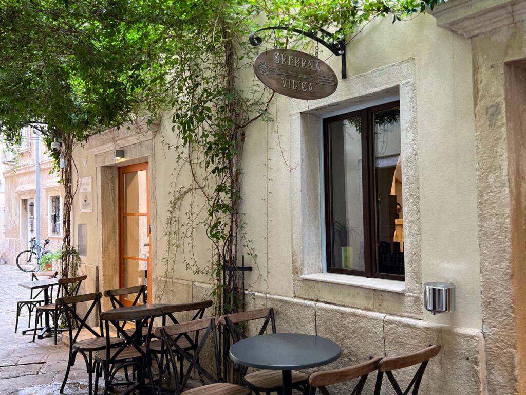 Hanging greenery creates a pergola over al fresco bistro chairs in Piran, Slovenia.