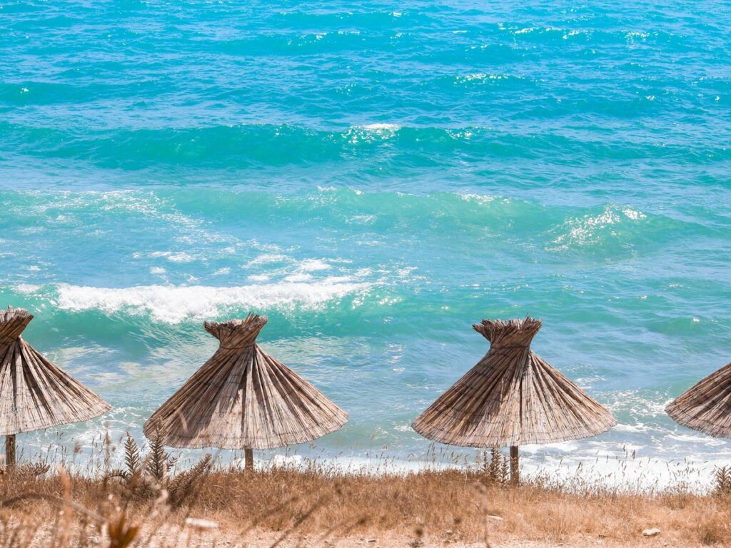 Straw umbrellas line the shore in Baska, Croatia.