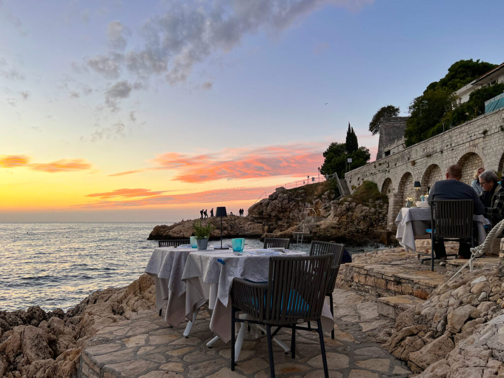 A dinner table sits on the rocks above the Adriatic at dusk, at La Puntulina in Rovinj, Croatia.