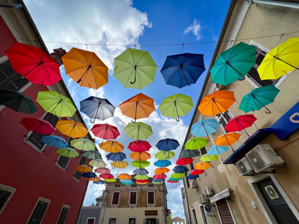 Colorful umbrellas hang above a street in Novigrad, Croatia.