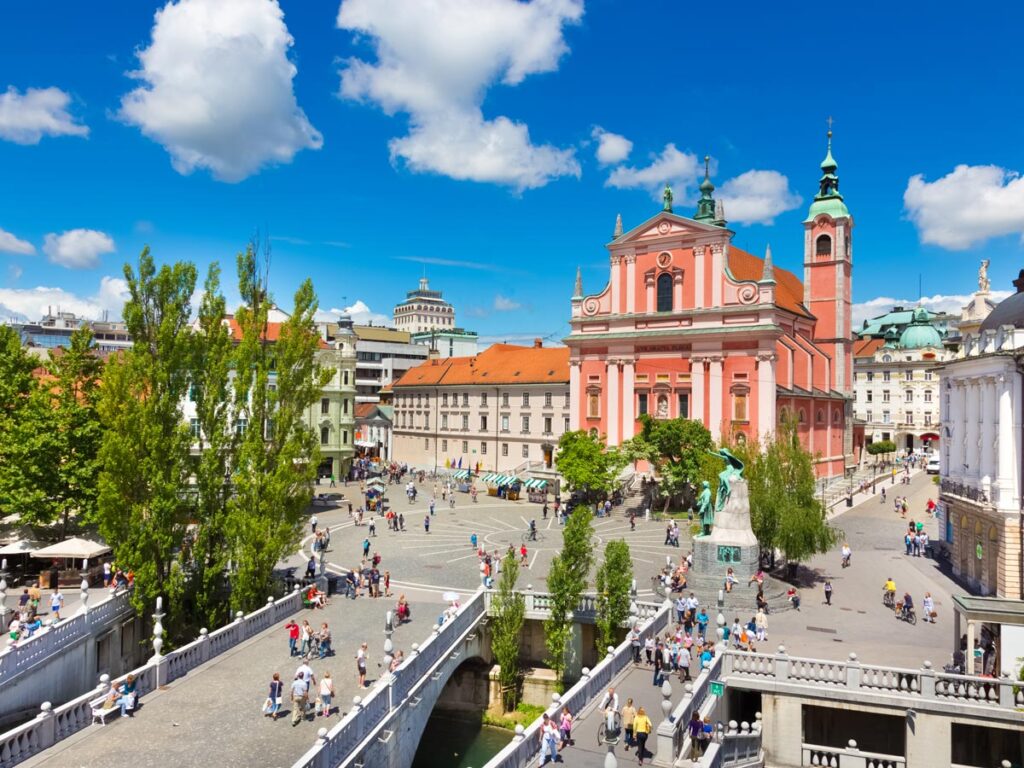 Preseren Square, anchored by the pink-hued Franciscan Church and Triple Bridge, in Ljubljana, Slovenia.