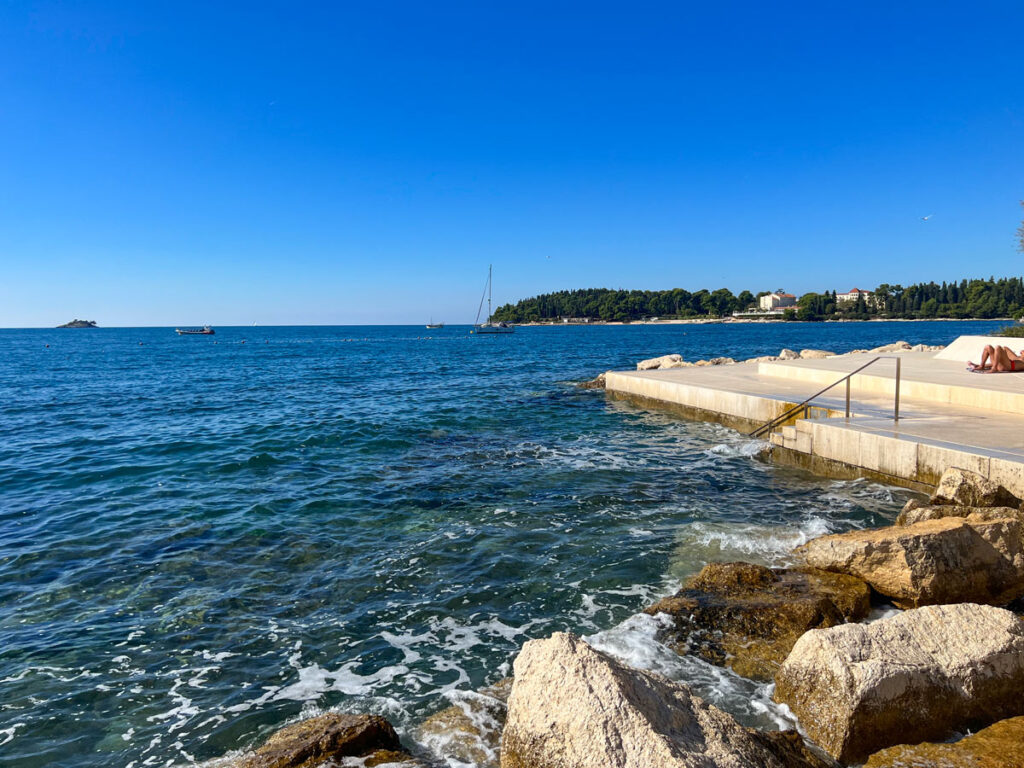 Sunbathers lounge at a public beach in Rovinj, Croatia along the Adriatic.