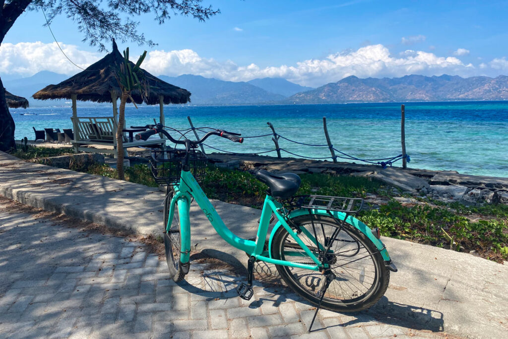 A bicycle rests in the shade on Gili Air island, looking across the Lombok Strait.