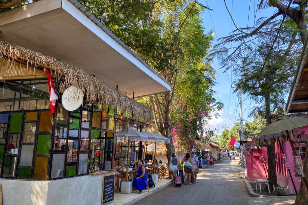 Vacationers stand along the tropical main street of Indonesia's Gili Air island, as seen from the thatched roof of Kopi Susu cafe.