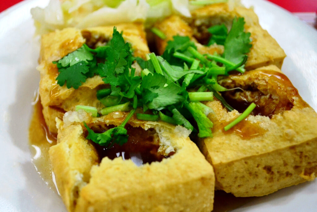 Fried stinky tofu, a street food staple in Taiwan, is shown in detail with chopped cilantro.