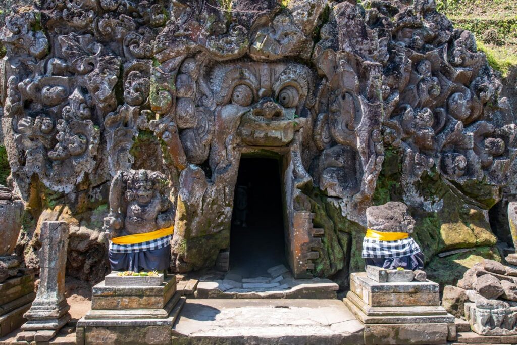 The entrance to Goa Gajah, also known as the Elephant Cave, displays the open-mouthed face of a Hindu deity carved into stone in Ubud, Bali.