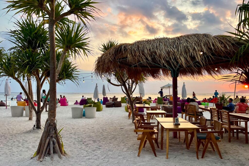 Diners sit along the southwestern shore of Gili Air, considered one of the best beaches on Gili Air for sunset.