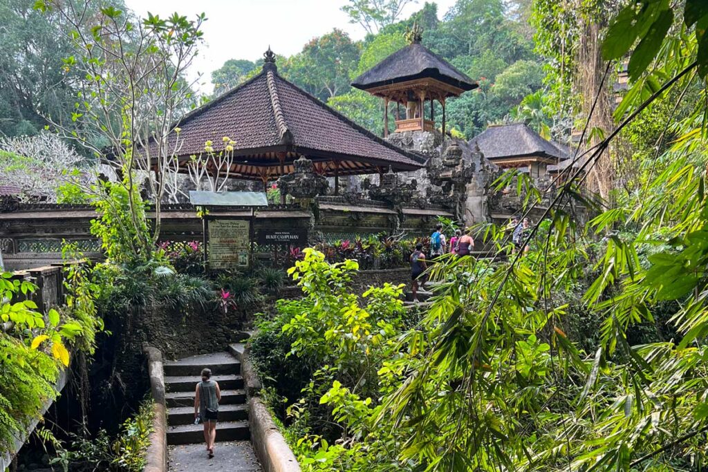 A lone figure walks along a footpath in Ubud, Bali besides Pura Gunung Lebah temple. When visitors consider where to go in Bali, Ubud is consistently one of the top destinations.