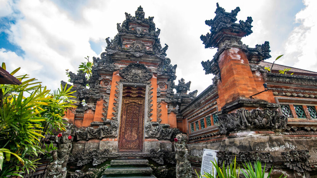 The brick facade of Saraswati Temple in Ubud, Bali, is detailed with intricate stone carvings and a Hindu motif.