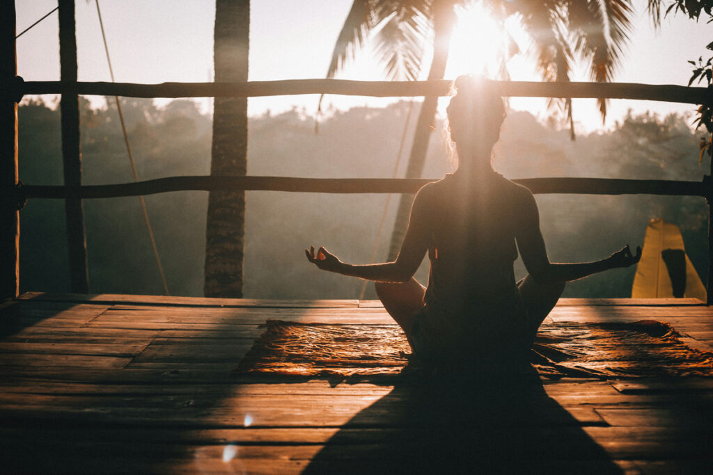 A lone woman sits cross-legged as she practices yoga inside an open-air tree house in Ubud, Bali.