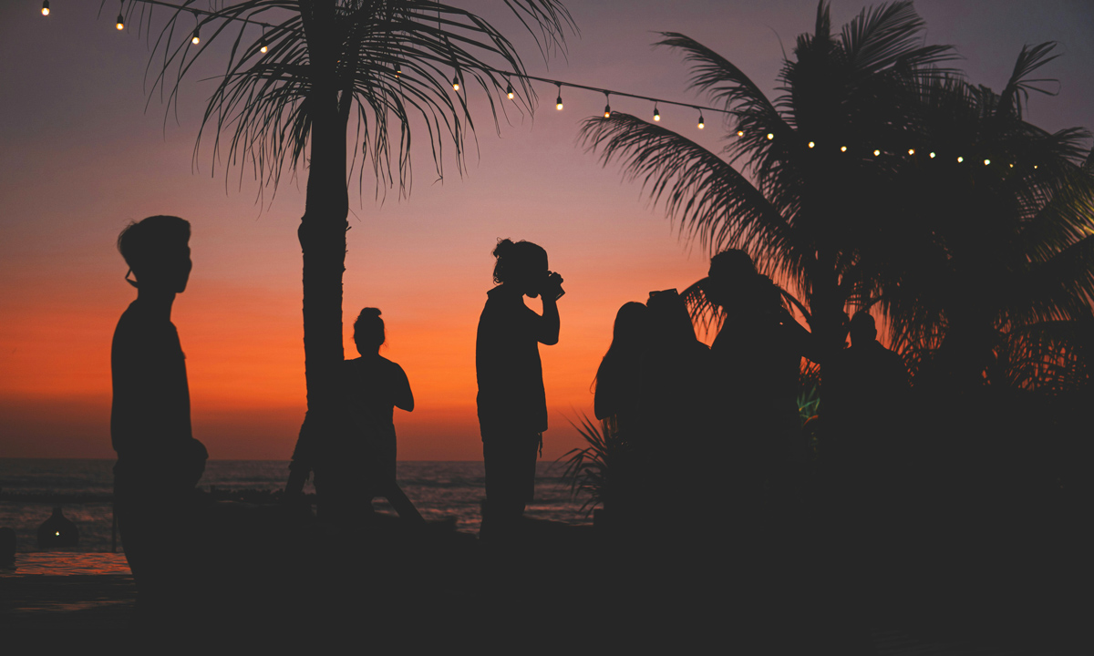 Diners are silhouetted against a beach sunset at The Lawn in Canggu, Bali.