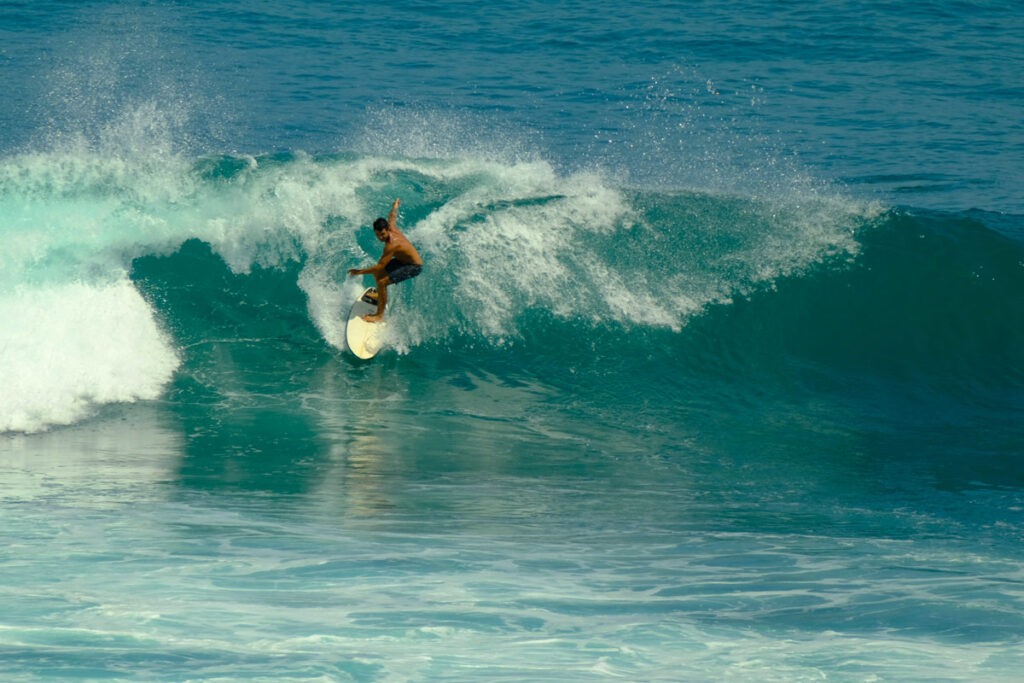 A man wearing board shorts surfs an advanced wave in Uluwatu, Bali. 