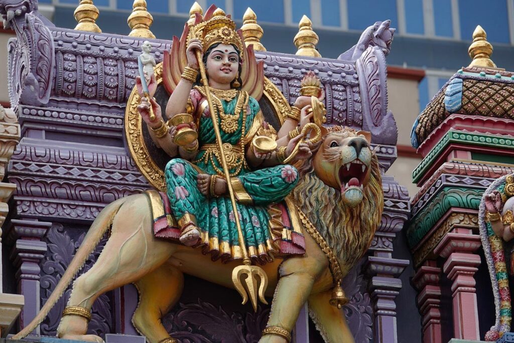 A brightly-painted statue of an Indian woman in traditional dress, sitting atop a lion, is shown in detail in Singapore's Little India neighborhood