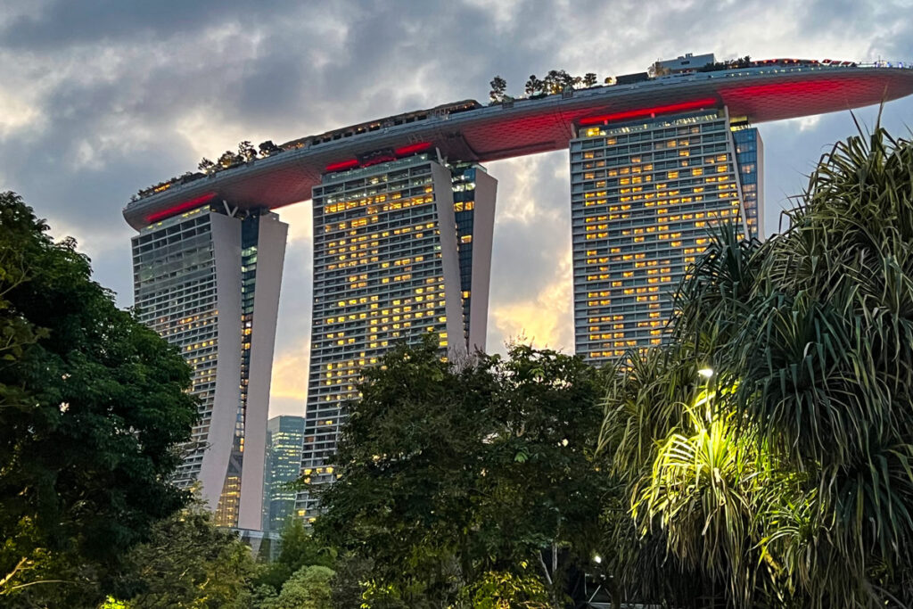 Singapore's Marina Bay Sands hotel, looking up to the SkyPark observation deck, is illuminated against a cloudy twilight sky