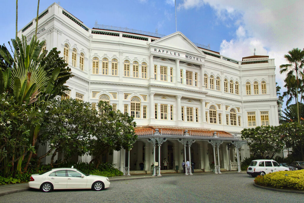 The front entryway of Singapore's iconic Raffles Hotel, with classic colonial architecture framed by tropical palms