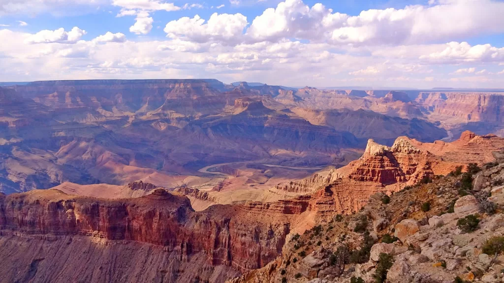 A panorama of Grand Canyon National Park is seen at sunset, with vivid hues lighting up the distant rock formations.