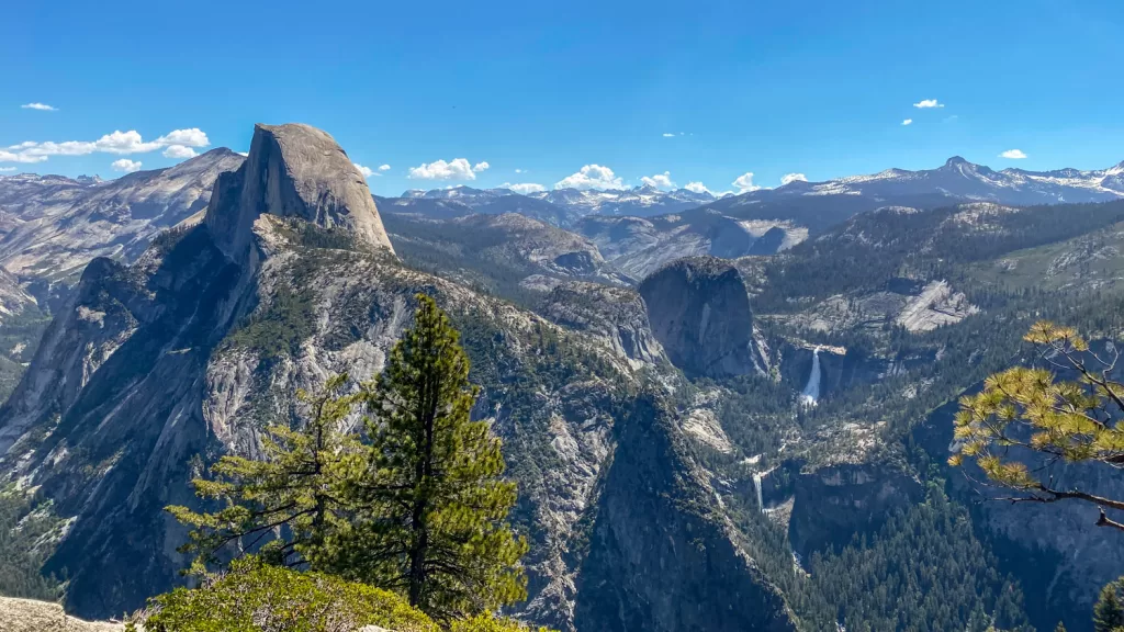 The view from Glacier Point out looks to Half Dome featured prominently in the foreground, with waterfalls and mountains stretching to the horizon.