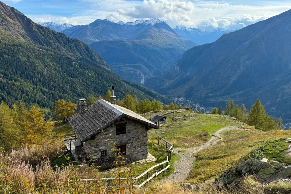 A small stone hut sits on an expansive Alpine ridge overlooking Courmayeur, Italy.