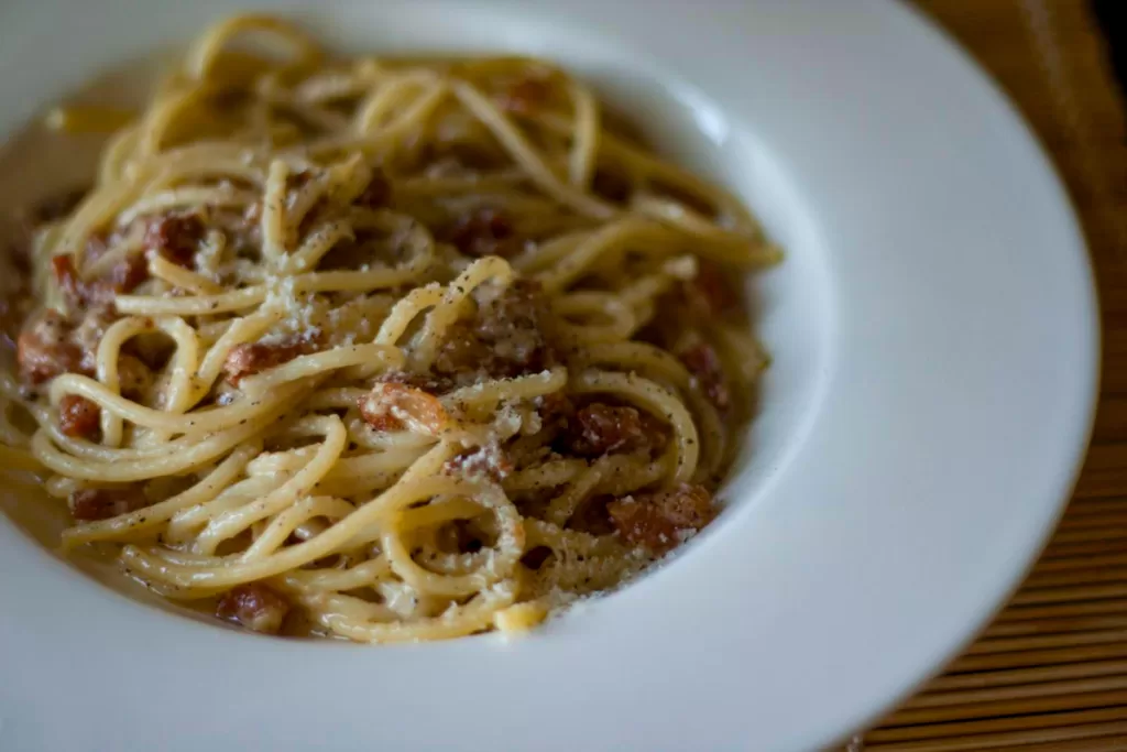 A bowl of pasta alla Gricia, with guanciale, pecorino cheese, and pepper.