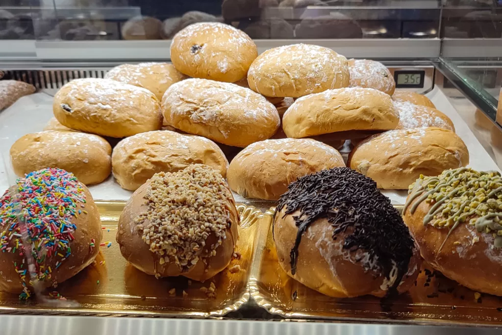 Maritozzi are displayed behind a bakery counter in Rome, Italy. When choosing what to eat in Rome, Maritozzi are the iconic local dessert.