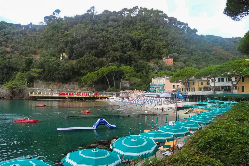 Teal beach umbrellas line the protected shore of Paraggi Beach outside of Portofino, Italy.