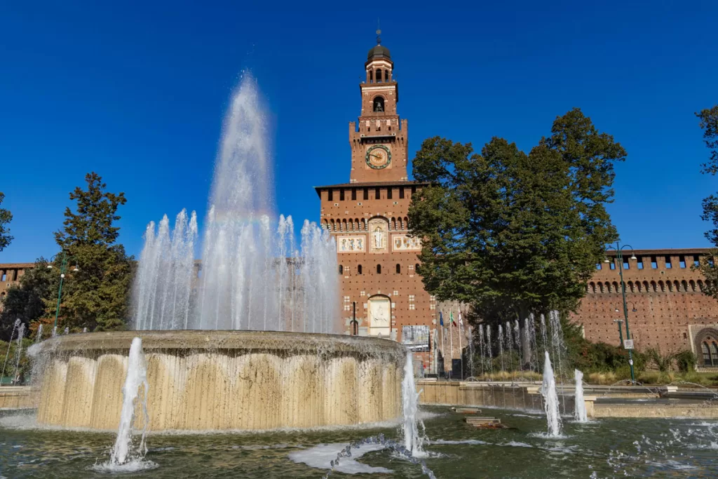 The hint of a rainbow is reflected in the waters of a large fountain in front of Sforza Castle in Milan, Italy.