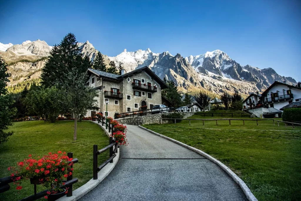 A traditional Alpine home sits against a backdrop of tall snowcapped peaks near Courmayeur in Italy's Aosta Valley.