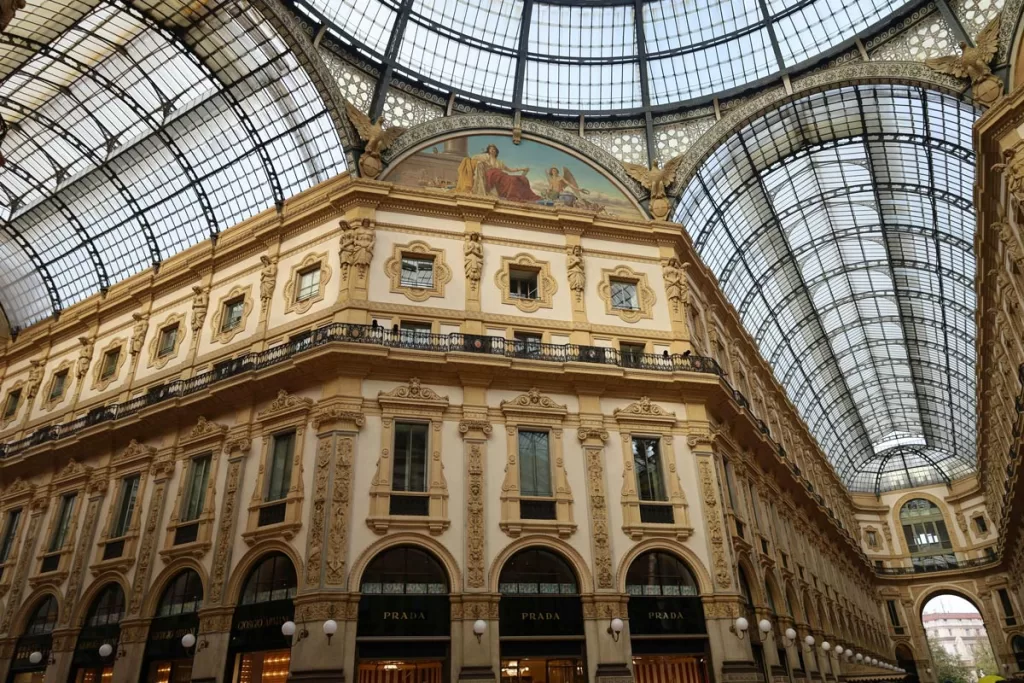Milan's iconic Galleria Vittorio Emanuele II shopping arcade is seen from the ground floor, looking up towards its glass and iron domed ceiling.