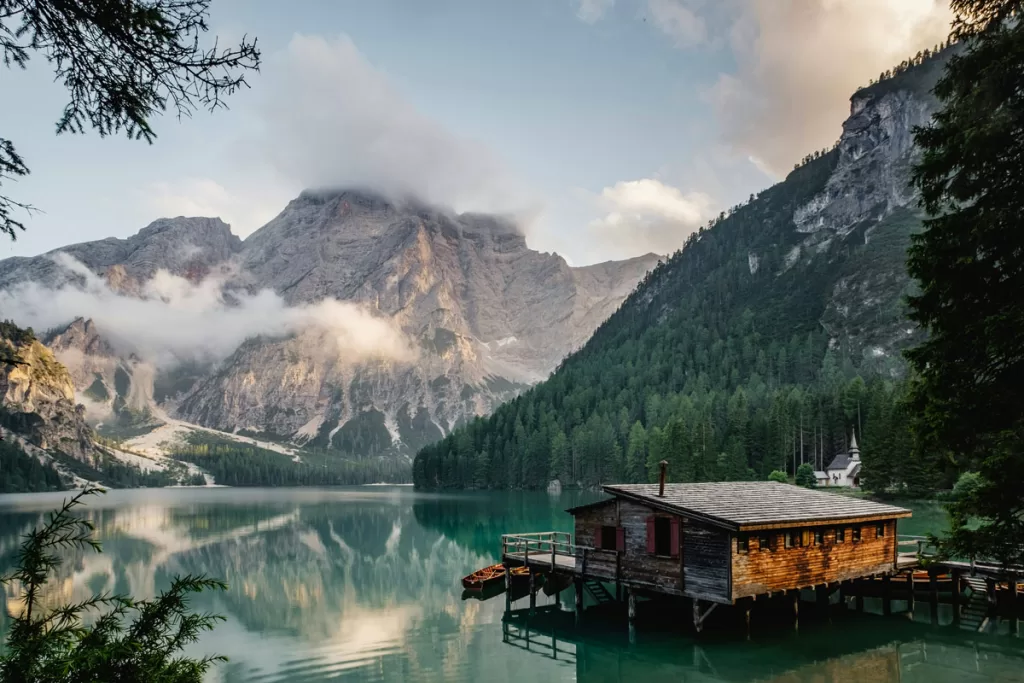 A solitary wooden boathouse sits over the placid waters of Lago di Braies in the Italian Dolomites.