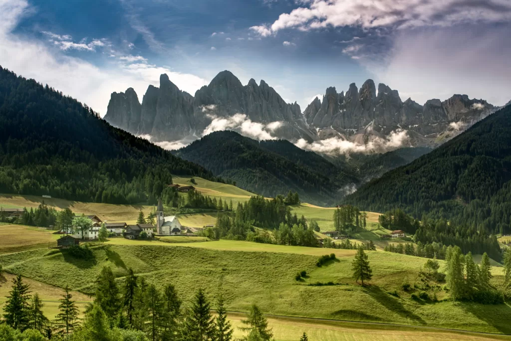 The tiny church of Santa Maddalena sits nestled in Italy's picturesque Val di Funes, beneath towering mountain peaks. This image is one of the most iconic Dolomites photo spots.